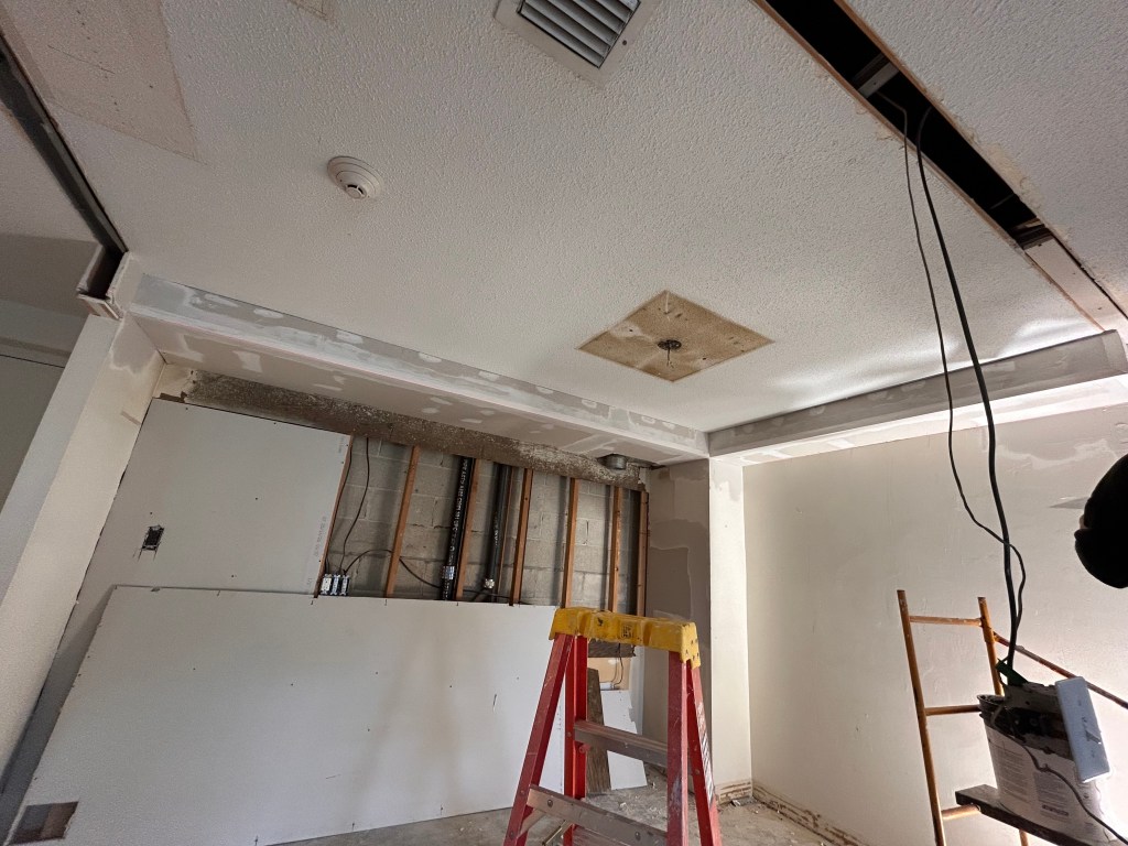 Drywall soffit and wall repair in progress inside a concrete-block building