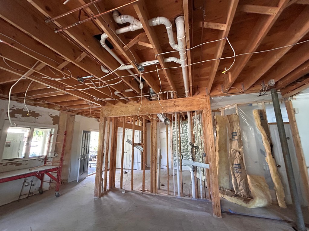 Gutted first floor with exposed joists, plumbing and wiring during a home renovation
