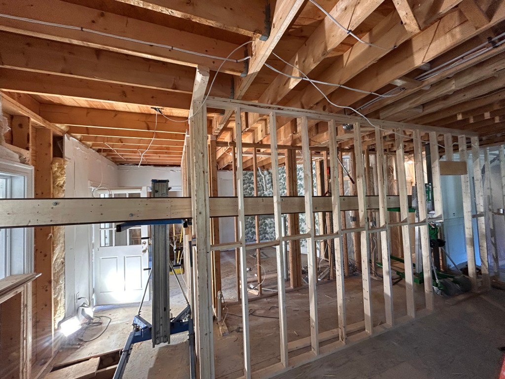 New stud wall framed beneath an engineered beam during a home renovation