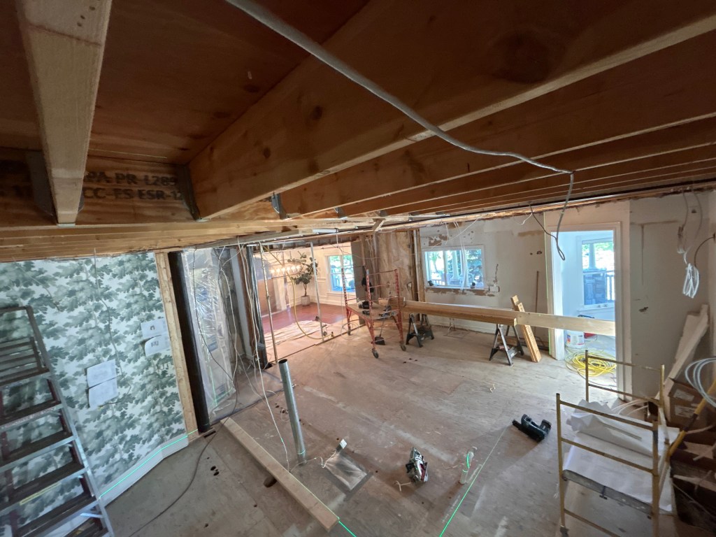 Open floor plan after wall removal, with a new engineered beam and joist hangers overhead